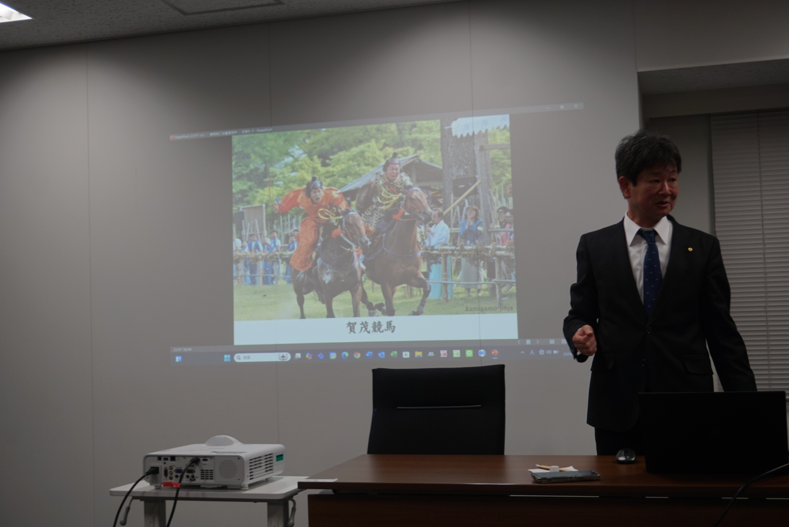 スクリーンに上賀競馬の写真が映し出されている研究会会場の全景。